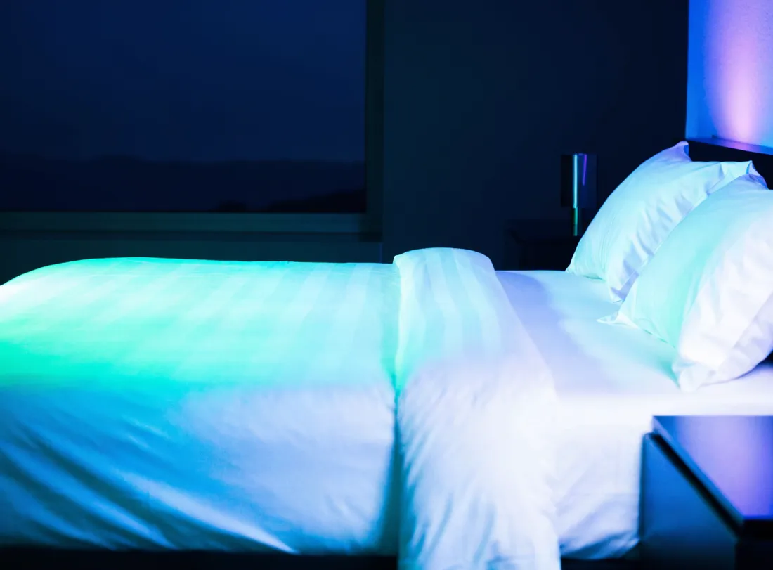 A freshly turned-over modern bedroom with crisp linens at night